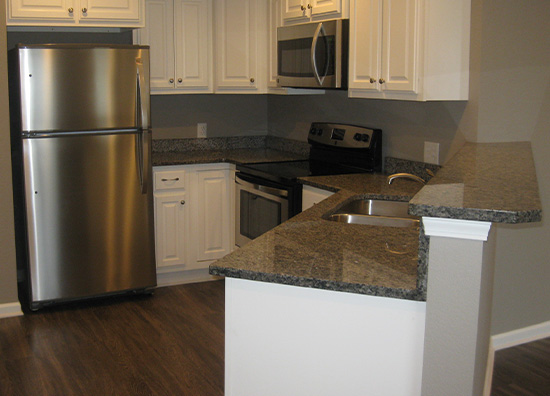 A luxury apartment kitchen with white cabinets and stainless steel appliances