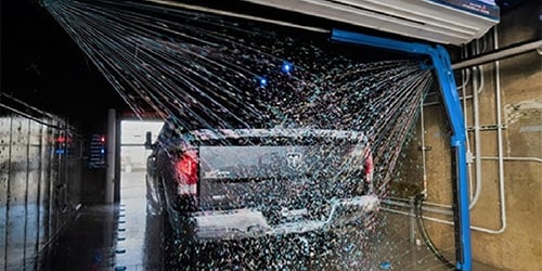 A truck being sprayed with soap in a 10th and Thompson touchless car wash bay